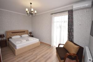1 dormitorio con 1 cama, 1 silla y 1 ventana en Hotel & Restaurant Sokhumi, en Zugdidi