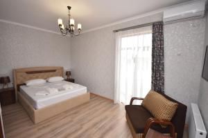 a bedroom with a bed and a chair and a window at Hotel & Restaurant Sokhumi in Zugdidi