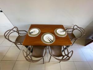 uma mesa de madeira com pratos e garfos em Apto Funcional próximo a Orla do Centro HS4 em Ubatuba