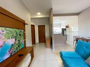 uma sala de estar com um sofá azul e uma televisão de ecrã plano em Apto Funcional próximo a Orla do Centro HS4 em Ubatuba