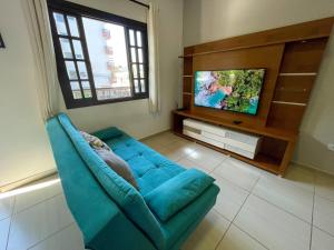 a living room with a blue couch and a tv at Apto Funcional próximo a Orla do Centro HS4 in Ubatuba