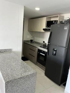 a kitchen with a black refrigerator and a stove at Habitación Auxiliar en Apto Compartido piso 26 in Bucaramanga