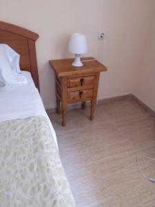 um quarto com uma cama e uma mesa com um candeeiro em Victoria Hospedaje em Alicante