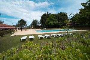 une piscine avec un groupe de chaises longues blanches et une piscine dans l'établissement Kampaoh Ruiloba, à Liandres