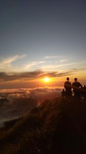 tres personas de pie en una colina viendo la puesta de sol en Zelobi Venture en Kintamani