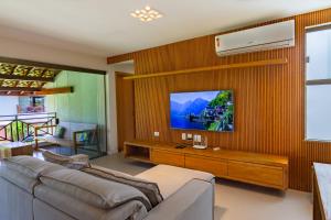 a living room with a couch and a tv on a wall at Ykutiba Imbassaí - Apartamento Superior - I104 in Imbassai