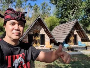 a man giving a thumbs up in front of a small house at Zelobi Venture in Kintamani