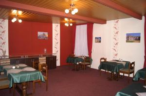 een eetkamer met tafels en stoelen en rode muren bij Pension Zur Sonne in Mansfeld