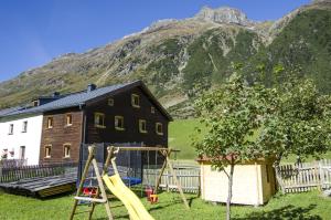 a playground in front of a house with a mountain at Appart Gidis in Galtür