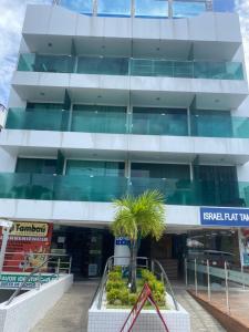 a building with a palm tree in front of it at Ravenna Imóveis - Flats Mobiliados Tambaú in João Pessoa