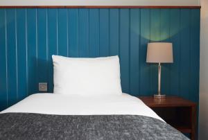 um quarto com uma cama e uma parede azul em The Longshoot em Nuneaton