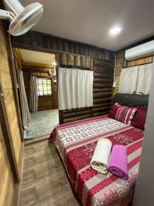 - une chambre avec un lit et une couverture rouge dans l'établissement HOMESTAY DUSUN ANA BALUN, à Slim River