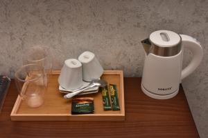 uma bandeja com comodidades para preparar café e copos numa mesa em Hotel & Restaurant Sokhumi em Zugdidi