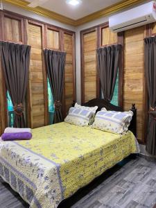 - une chambre avec un lit et une couette jaune dans l'établissement HOMESTAY DUSUN ANA BALUN, à Slim River