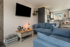 a living room with two blue couches and a tv at Sycamore Cottage in Tenby