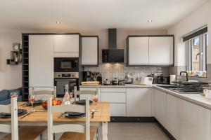 a kitchen with white cabinets and a table and chairs at Sycamore Cottage in Tenby