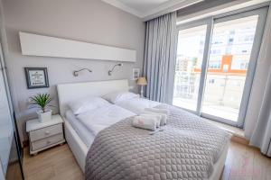 a bedroom with a white bed and a large window at Your Holidays Promenada Gwiazd 28 in Międzyzdroje