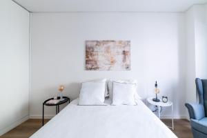 a white bedroom with a bed and two blue chairs at Lusíadas 53 4ºE - Beautiful River View in Lisbon