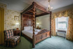 a bedroom with a canopy bed and a chair at The Portland Hotel in Lybster