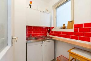 cocina con azulejos rojos, fregadero y ventana en Aranykez 4-6: Downtown studio, en Budapest