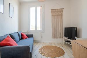 een woonkamer met een blauwe bank en een televisie bij Duplex, vue mer, proche du centre ville, 4P in Toulon