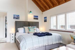 a bedroom with a large bed and windows at Linden House in West Wittering