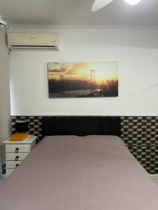 1 dormitorio con 1 cama y una pintura en la pared en Apartamento no Centro, en Florianópolis