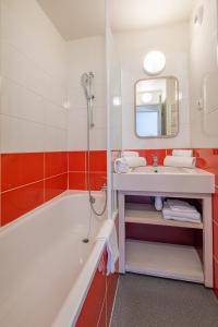 La salle de bains est pourvue d'une baignoire, d'un lavabo et d'un miroir. dans l'établissement Résidence Pierre & Vacances La Daille, à Val dʼIsère