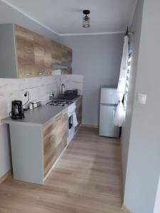 eine Küche mit weißen Geräten und Holzschränken in der Unterkunft Domek z ogrodem in Mątki