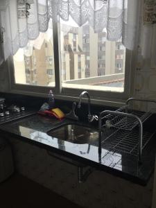 eine Küchentheke mit einem Waschbecken und einem Fenster in der Unterkunft Apartamento no Centro in Florianópolis