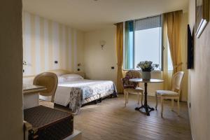 une chambre d'hôtel avec un lit, une table et des chaises dans l'établissement Hotel London, à Viareggio