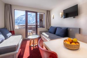 a living room with a couch and a table with a bowl of fruit at Résidence Pierre & Vacances La Daille in Val-d'Isère