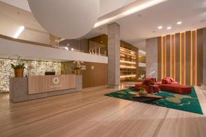 a lobby with a red couch and a reception desk at Suryaa Hotel Pinhais, Curio Collection by Hilton in Pinhais