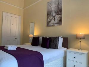 a bedroom with two beds with purple sheets and two lamps at ALTIDO Adorable flat near West End in Edinburgh