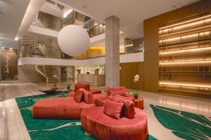 un vestíbulo del hotel con 2 camas rojas y una escalera en Suryaa Hotel Pinhais, Curio Collection by Hilton, en Pinhais
