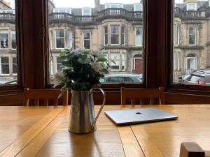 a vase of flowers sitting on a table with a laptop at ALTIDO Adorable flat near West End in Edinburgh