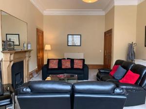 a living room with two leather couches and a fireplace at ALTIDO Adorable flat near West End in Edinburgh