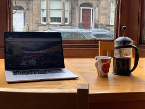 a laptop computer sitting on a table next to a cup of coffee at ALTIDO Adorable flat near West End in Edinburgh