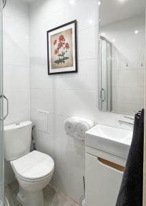 a white bathroom with a toilet and a sink at Flower House Warsaw Chopin Airport in Warsaw