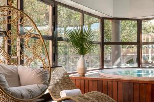 Habitación con silla y bañera con ventana en Golf Hôtel de Valescure & Spa NUXE, en Saint-Raphaël