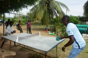 Un uomo che gioca a ping pong su un tavolo di Adomi Bridge Garden a Adome