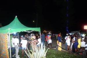 una folla di persone in piedi sotto una tenda verde di Adomi Bridge Garden a Adome