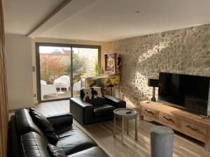a living room with a leather couch and a flat screen tv at Le Clos Des Coteaux in Trigny