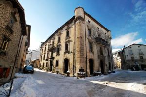 - un vieux bâtiment en pierre dans une rue enneigée dans l'établissement Hotel Le Torri, à Pescocostanzo