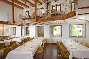 Hotel der Löwen in Staufen في ستوفت ام بريسغو: غرفة بها طاولات بيضاء وكراسي ونوافذ