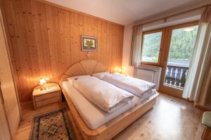 1 dormitorio con 1 cama en una pared de madera en Haus Adlerhorst, en Ultimo