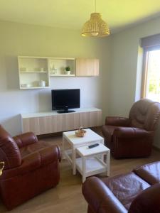 a living room with two couches and a flat screen tv at EL RINCON DE PARRES in Parres de Llanes