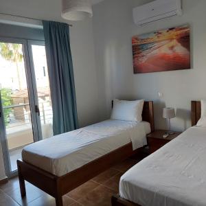 una camera d'albergo con due letti e una finestra di Manolakis House a Kardámaina