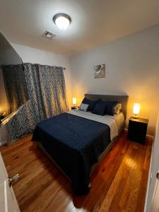 a bedroom with a bed with blue sheets and two lamps at SPRINGVIEW HOMES 12MINS FROM EWR & 3 MINS FROM UNIVERSITY HOSPITAL in Newark