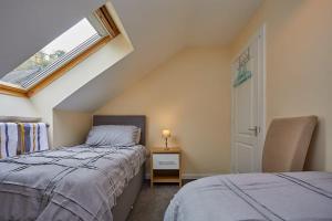 1 dormitorio en el ático con 2 camas y ventana en Campbells Loft en Oban